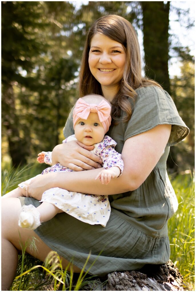 Madison holding baby Olivia, both smiling in the Cedarpines Park forest