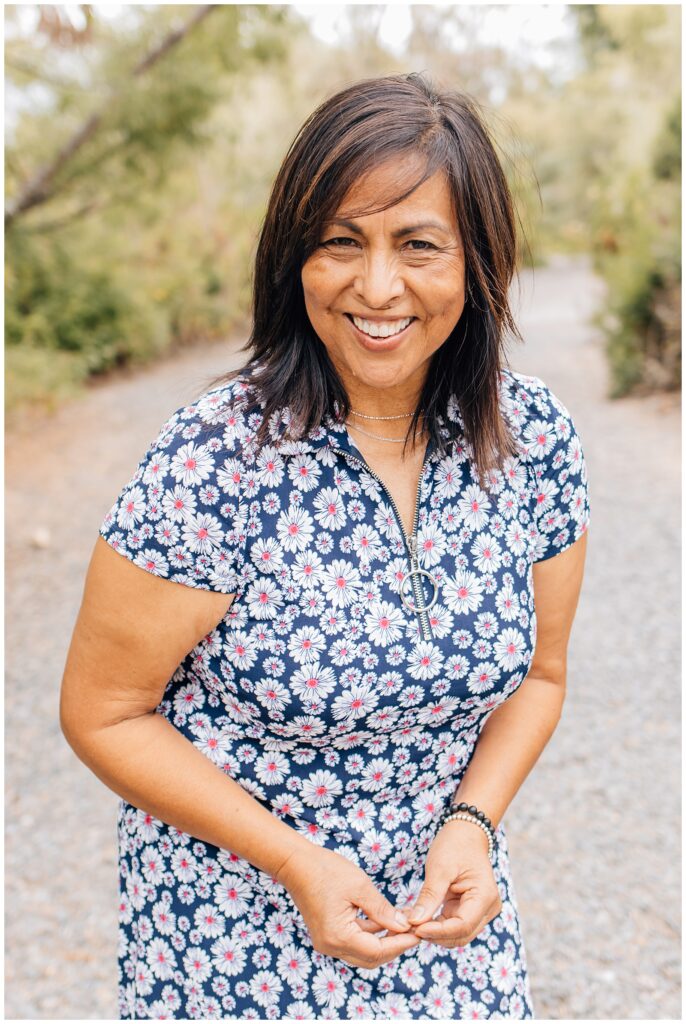 Portrait of the mother smiling brightly at the camera while standing on a nature trail.