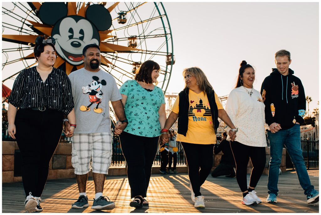 Family walking across the bridge at Pixar Pier with the Pixar Pal-A-Round in the background